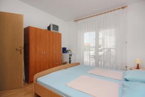 una camera da letto con un letto blu e una finestra di Apartments and rooms with parking space Sveti Vid, Krk - 5323 a Sveti Vid-Miholjice