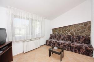 a living room with a couch and a tv at Apartments by the sea Njivice, Krk - 5311 in Njivice
