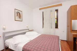 a bedroom with a bed with a pink and white blanket at Apartments by the sea Njivice, Krk - 5311 in Njivice