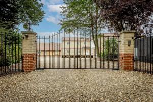 an iron gate with a building in the background at Cottage In Norfolk Sleeps 23 - Private Pool, Fishing Lake, Hot Tub Ref 99008sc in Hockham