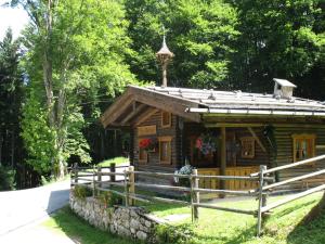 eine Blockhütte im Wald mit einem Zaun in der Unterkunft Almbrünnerl die Almhütte auf der Raffner Alm in Ruhpolding