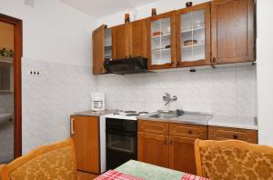 a kitchen with wooden cabinets and a stove top oven at Apartments with a parking space Baska, Krk - 5411 in Baška
