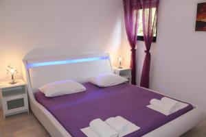 sypialnia z fioletowym łóżkiem z 2 ręcznikami w obiekcie Apartments with a parking space Artatore, Losinj - 5377 w mieście Čunski