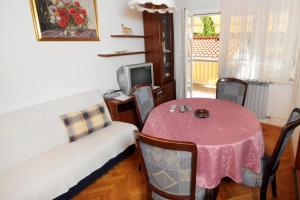 a room with a table and a couch and a tv at Apartments with a parking space Selce, Crikvenica - 5495 in Selce
