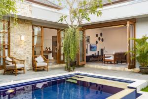 an outdoor living area with a swimming pool and a house at Bali Voyage in Seminyak