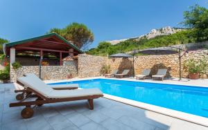 a swimming pool with a chaise lounge chairs and a swimming pool at Apartments with a swimming pool Baska, Krk - 5354 in Baška