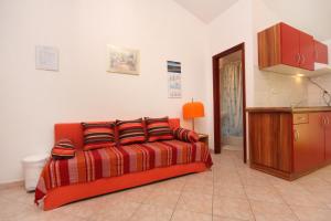 an orange couch with pillows in a room at Apartments with a swimming pool Baska, Krk - 5354 in Baška