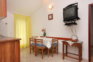 a dining room with a table and a tv on the wall at Apartments with a swimming pool Baska, Krk - 5354 in Baška
