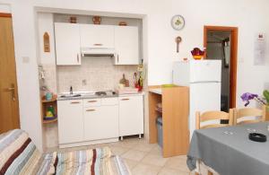 a small kitchen with white cabinets and a table at Apartments with a parking space Pinezici, Krk - 5319 in Pinezici