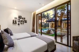 two beds in a bedroom with a view of a pool at Villa Manga by BaliSuperHost in Ubud