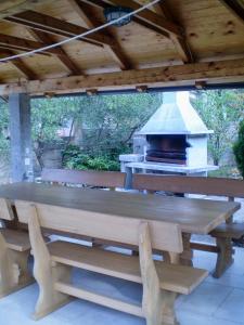 drewniany stół i ławki pod dachem z grillem w obiekcie Apartment Pinezici 5319b w mieście Pinezići