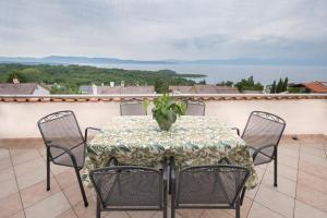 a table with chairs and a vase on a balcony at Apartments with a parking space Njivice, Krk - 5427 in Njivice