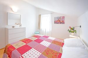 a bedroom with a bed with a colorful quilt on it at Apartment Njivice 5427b in Njivice