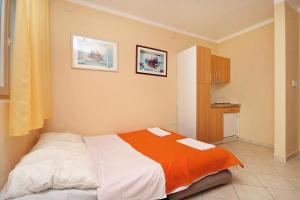 a bedroom with a bed with an orange and white blanket at Studio Baska 5450b in Baška