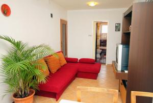 a red couch in a living room with a tv at Apartments and rooms by the sea Dramalj, Crikvenica - 5519 in Dramalj