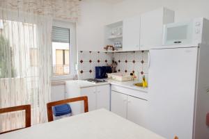 a kitchen with white cabinets and a white refrigerator at Apartments and rooms by the sea Dramalj, Crikvenica - 5519 in Dramalj