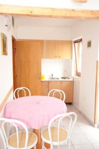 a kitchen with a pink table and chairs at Apartment Njivice 5398a in Njivice