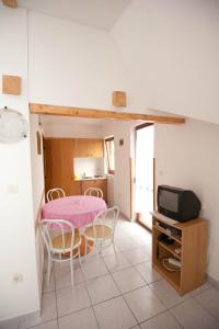 a room with a table and chairs and a tv at Apartment Njivice 5398a in Njivice