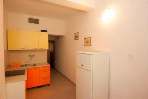 a kitchen with a white refrigerator and orange cabinets at Apartment Njivice 5398h in Njivice