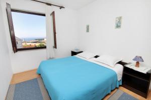 - une chambre avec un lit bleu et une fenêtre dans l'établissement Apartments with a parking space Krk - 5321, à Krk