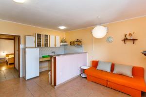 a living room with an orange couch and a kitchen at Apartments with a parking space Kornic, Krk - 5306 in Kornić