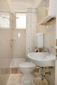 a bathroom with a toilet and a sink and a tub at Apartments with a parking space Krk - 5371 in Krk