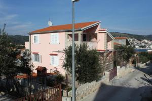 una casa rosa con una valla y una calle en Apartments by the sea Businci, Ciovo - 5256 en Trogir