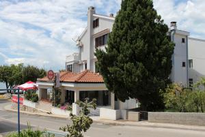 Biały budynek z drzewem przed nim w obiekcie Apartments by the sea Punat, Krk - 5328 w mieście Punat