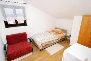 een slaapkamer met een bed en een rode stoel bij Apartments by the sea Punat, Krk - 5328 in Punat