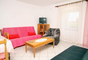 Apartments by the sea Punat, Krk - 5329 في بونات: غرفة معيشة مع أريكة وطاولة