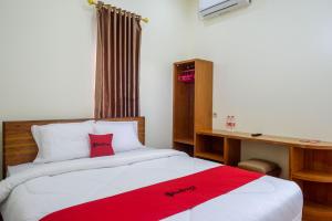 een slaapkamer met een bed, een bureau en een rode deken bij RedDoorz near Rita Supermall Purwokerto 2 in Purwokerto