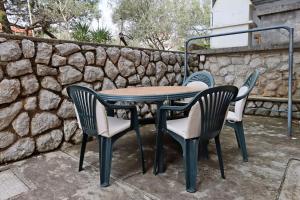 einen Tisch und Stühle auf einer Terrasse mit einer Steinmauer in der Unterkunft Apartments with a parking space Punat, Krk - 5410 in Punat