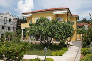 a yellow house with a tree in front of it at Apartment Punat 5408a in Punat