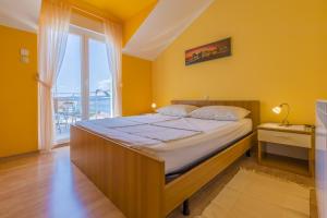 a bedroom with a large bed with yellow walls and a window at Apartments by the sea Selce, Crikvenica - 5367 in Selce