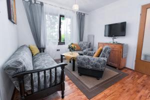 Apartments by the sea Punat, Krk - 5351 في بونات: غرفة معيشة مع أريكة وكراسي وتلفزيون