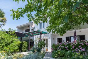 a white house with flowers in front of it at Apartment Punat 5351b in Punat