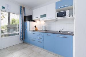 a blue kitchen with a sink and a microwave at Apartment Punat 5351b in Punat +22 photos