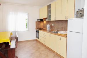 a kitchen with yellow cabinets and a white refrigerator at Apartments with a parking space Vantacici, Krk - 5425 in Vantačići
