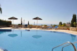 una gran piscina con sillas y sombrillas en Tala Hills, en Pafos
