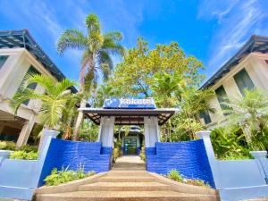 a hotel entrance with blue gates and palm trees at Kokotel Khao Lak Lighthouse in Khao Lak