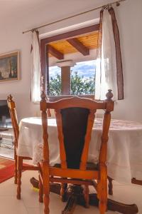 a wooden chair with a table in front of a window at Apartment Njivice 5362b in Njivice