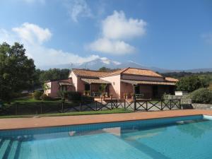 a villa with a swimming pool in front of a house at Agriturismo Le Case Del Merlo in Milo