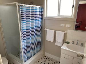a bathroom with a shower with a blue and white shower curtain at Lorsens on the River - Shoalhaven Heads in Shoalhaven Heads