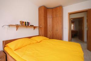 sypialnia z żółtym łóżkiem i drewnianą szafką w obiekcie Apartment Pinezici 5464c w mieście Pinezići