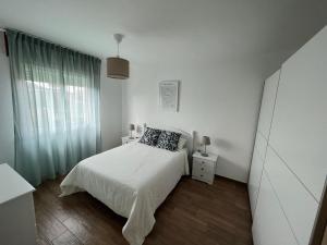 Habitación blanca con cama y ventana en Apartamento Bouzavella Panxón, en Nigrán