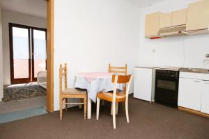 a kitchen with a table and chairs in a room at Apartments and rooms with parking space Stara Baska, Krk - 5447 in Stara Baška