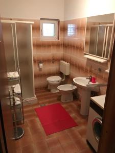a bathroom with two toilets and a shower and a red rug at Apartments with a parking space Smrika, Kraljevica - 5338 in Šmrika