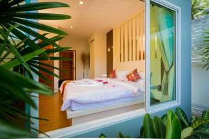 Schlafzimmer mit einem Bett mit weißer Bettwäsche und einem Fenster in der Unterkunft Irawan House in Ao Nang Beach