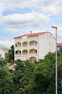 een wit gebouw met balkons op de top van bomen bij Apartments with a parking space Novi Vinodolski - 5526 in Novi Vinodolski