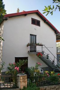 a white house with a balcony and flowers at Apartments with a parking space Selce, Crikvenica - 5531 in Selce